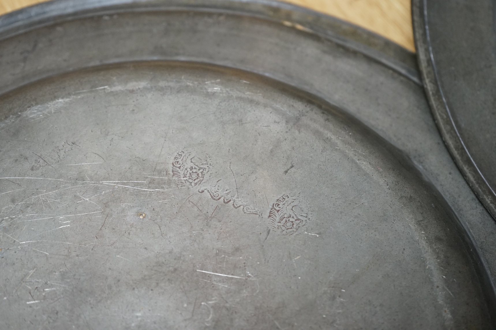 Three Pewter chargers, a large dish and a plate, c.1800, largest dish 42cm diameter (5)